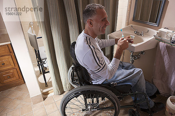 Mann mit Rückenmarksverletzung im Rollstuhl beim Zähneputzen