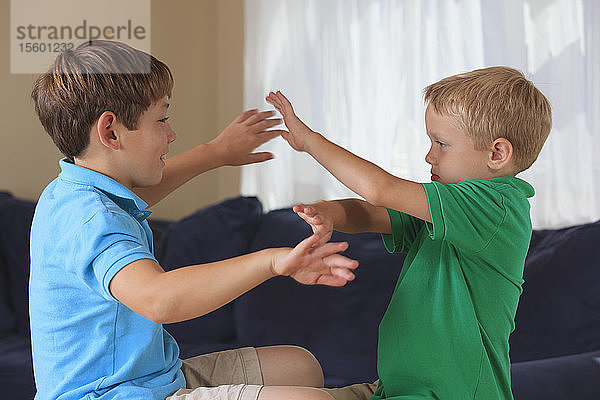 Jungen mit einer Hörbehinderung  die auf ihrer Couch in amerikanischer Gebärdensprache sicher gebärden