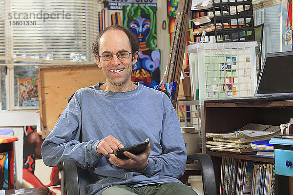 Mann mit Asperger-Syndrom bei der Arbeit an seinem Tablet in seinem Kunstatelier