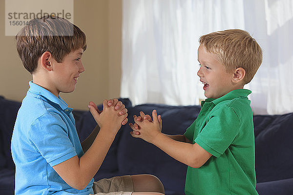 Hörgeschädigte Jungen gebärden auf ihrer Couch Wrestling in amerikanischer Zeichensprache