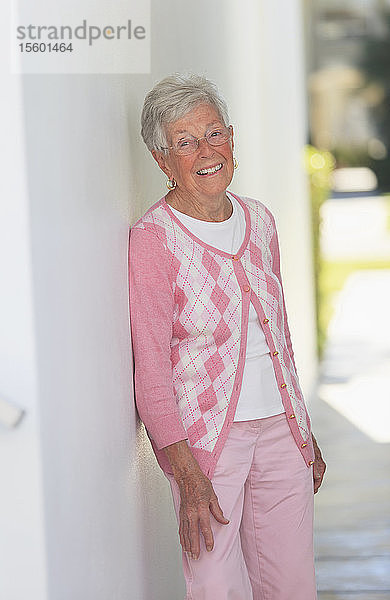 Ältere Frau lehnt lächelnd an einer Wand