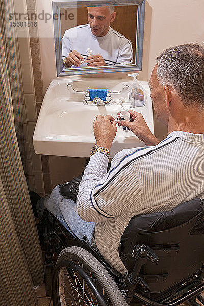 Mann mit Querschnittslähmung setzt in einer barrierefreien Toilette Kontaktlinsen ein