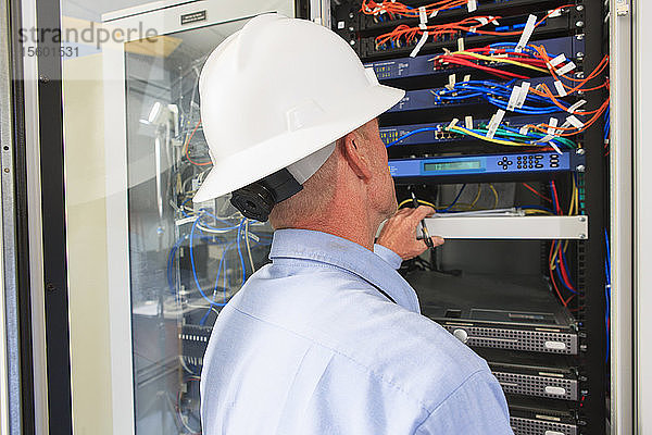 Ingenieur im Kontrollraum eines Elektrizitätswerks mit Blick auf Server und Schalter