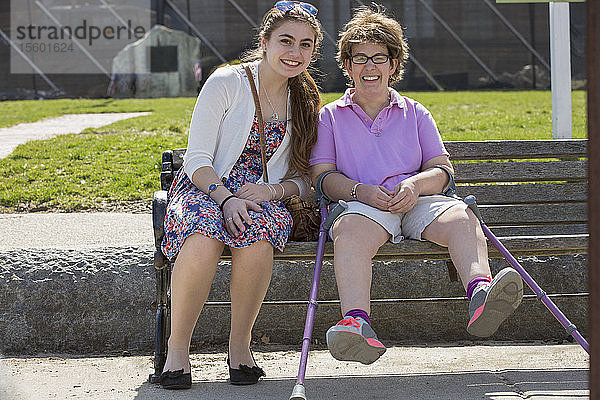 Frau mit zerebraler Lähmung sitzt mit ihrer Schwester in einem Park