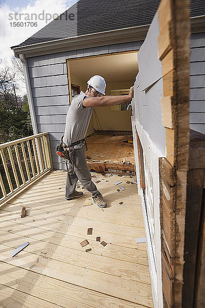 Hispanischer Schreiner beim Entfernen der neu geschnittenen Tür zum Deck eines Hauses