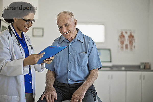 Ein lächelnder älterer Mann  der bei seiner jährlichen ärztlichen Untersuchung gute Nachrichten erhält