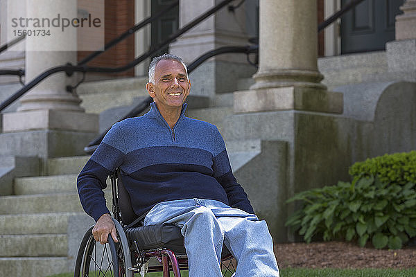 Mann mit Rückenmarksverletzung sitzt in einem Rollstuhl und lächelt