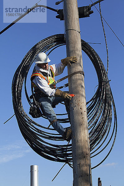 Kabelmonteur bei der Vorbereitung der Verlegung eines neuen Kabels vom Strommast