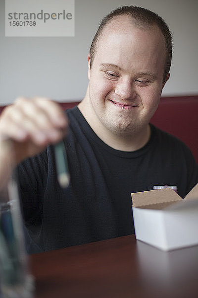 Glücklicher Kellner mit Down-Syndrom bei der Vorbereitung in einem Restaurant