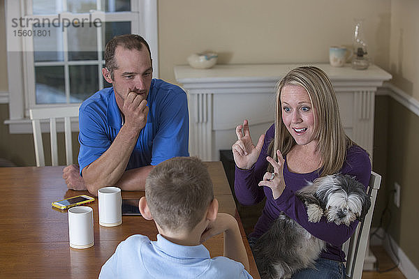 Familie mit Hörbehinderung sagt in amerikanischer Zeichensprache Basketball mit einem Hund zu Hause
