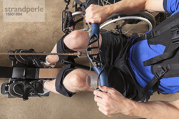 Ein Mann mit einer Rückenmarksverletzung benutzt sein Rudergerät  an dem ein Muskelstimulator angebracht ist