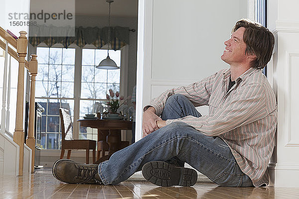 Mann sitzt zu Hause auf dem Boden