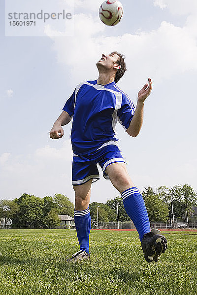 Junger Mann spielt mit einem Fußball.