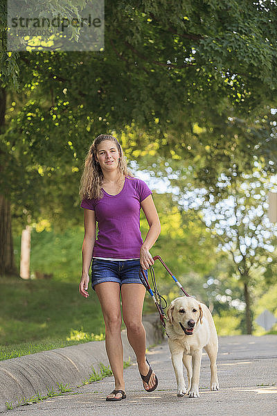 Frau mit Sehbehinderung geht mit ihrem Diensthund spazieren