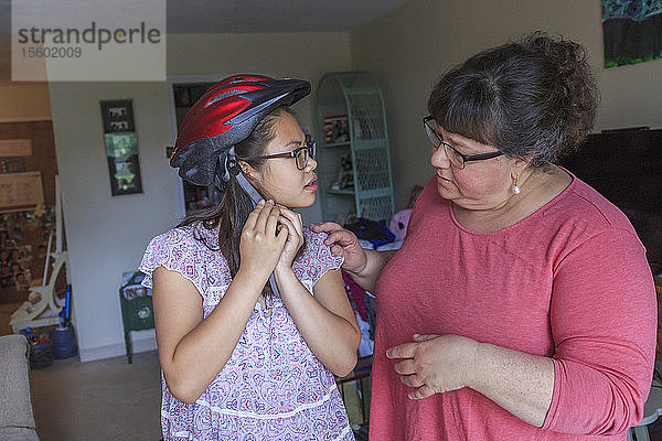 Lernbehindertes Teenager-Mädchen setzt mit ihrer Mutter den Helm auf