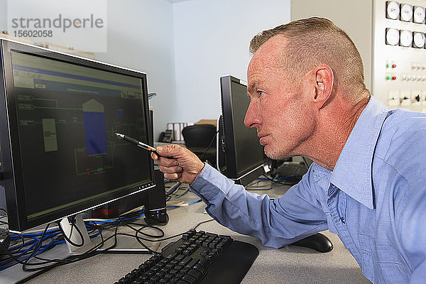 Ingenieur in der Leitwarte eines Elektrizitätswerks  der die Messwerte auf den Management-Displays überprüft