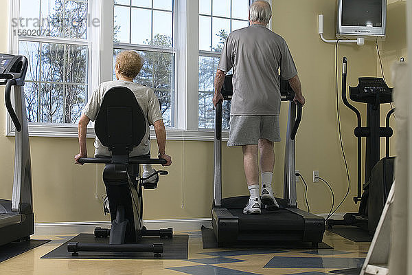 Ein älteres Paar trainiert im Fitnessstudio.