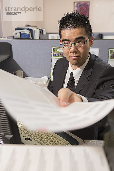 Asiatischer Mann mit Autismus erledigt Papierkram in einem Büro
