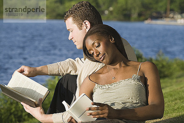 Nahaufnahme eines erwachsenen Paares  das in einem Park sitzt und Bücher liest