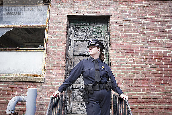 Blick auf eine Polizistin  die an der Treppe eines alten Hauses steht.