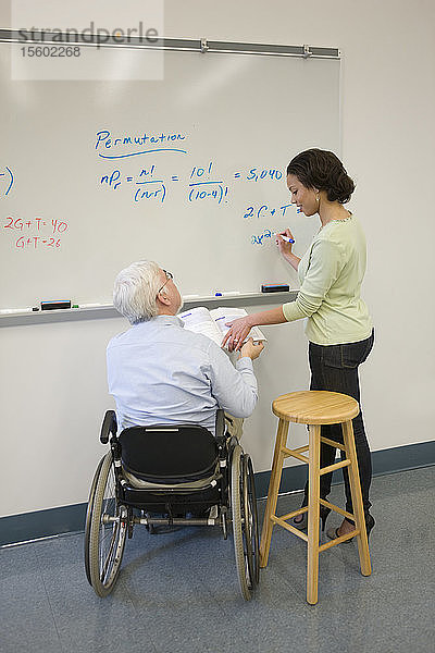 Universitätsprofessor mit Muskeldystrophie unterrichtet seine Studenten in einem Klassenzimmer