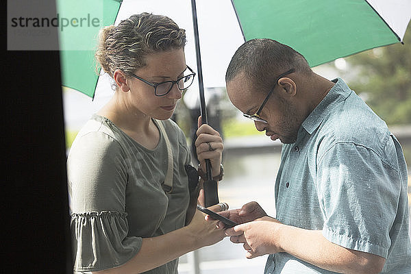 Afroamerikanischer Mann mit Down-Syndrom schaut mit seinem Freund auf sein Handy
