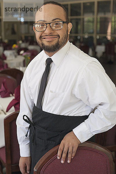 Porträt eines afroamerikanischen Mannes mit Down-Syndrom als Kellner in einem Restaurant