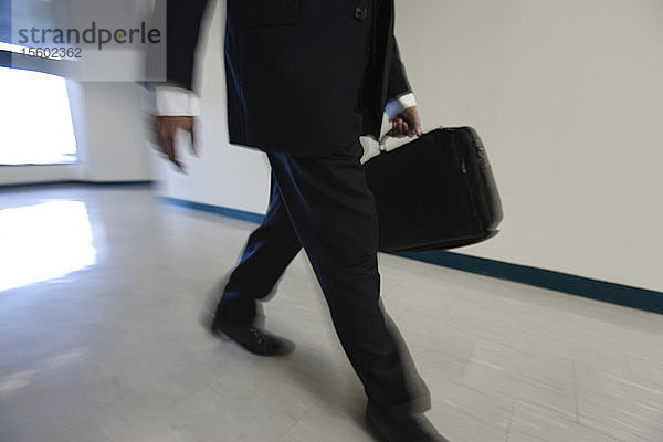 Ein junger Mann geht mit einer Aktentasche in einem Korridor.