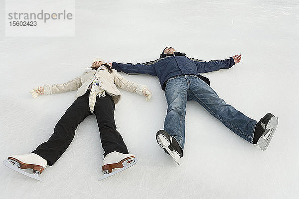 Junges Paar auf einer Eislaufbahn liegend
