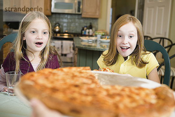 Blick auf zwei Mädchen  die sich eine Pizza ansehen.