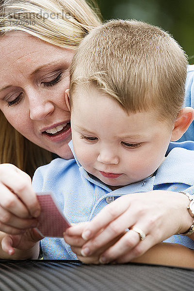 Blick auf eine Frau  die ihrem Sohn eine Spielkarte in amerikanischer Zeichensprache zeigt.