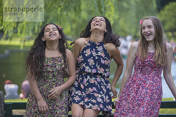 Glückliche hispanische Frau mit ihren Teenager-Töchtern mit Zahnspange  die in einem Park lachen