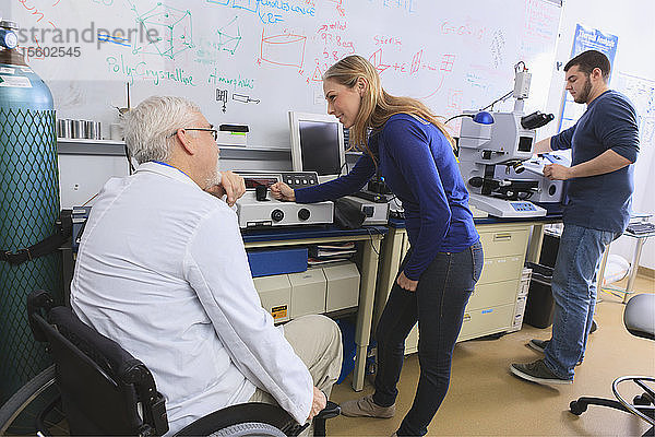Professor mit Muskeldystrophie berät Ingenieurstudenten im Chemielabor bei der Arbeit an Röntgenfluoreszenz-Analysatoren
