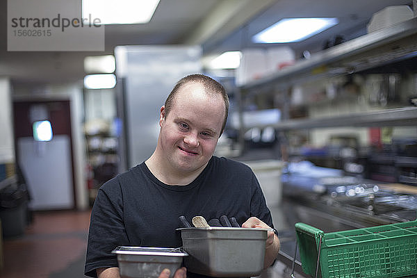 Kellner mit Down-Syndrom bei der Arbeit in der Küche eines Restaurants