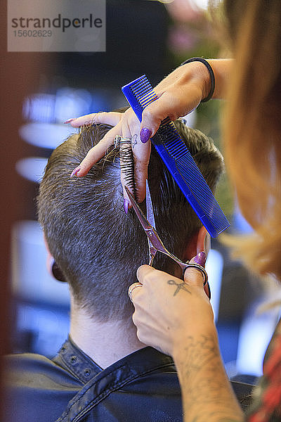 Ein Mann mit einer Rückenmarksverletzung lässt sich in einem Friseursalon die Haare schneiden