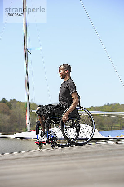 Mann im Rollstuhl mit Spinaler Meningitis an einem Segelhafen