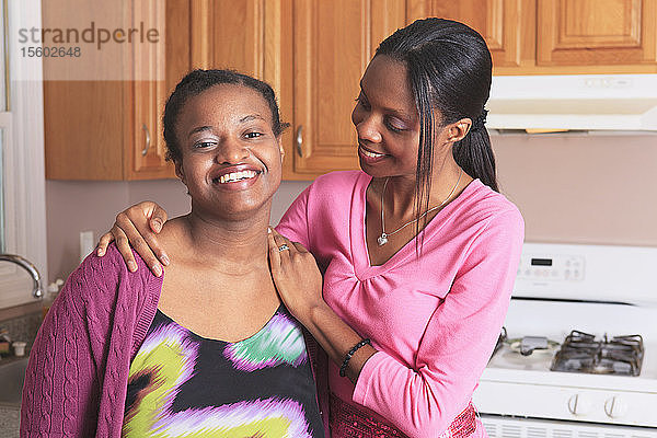 Zwei Schwestern lächeln in der Küche  eine mit einer Lernbehinderung