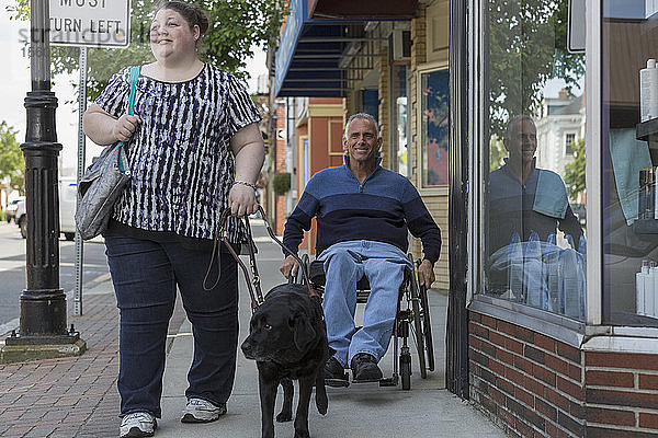 Mann mit Rückenmarksverletzung und seine Tochter gehen mit ihrem Diensthund einkaufen
