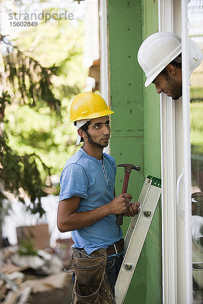 Zimmermann bei der Kontrolle des Einbaus eines neuen Fensterrahmens