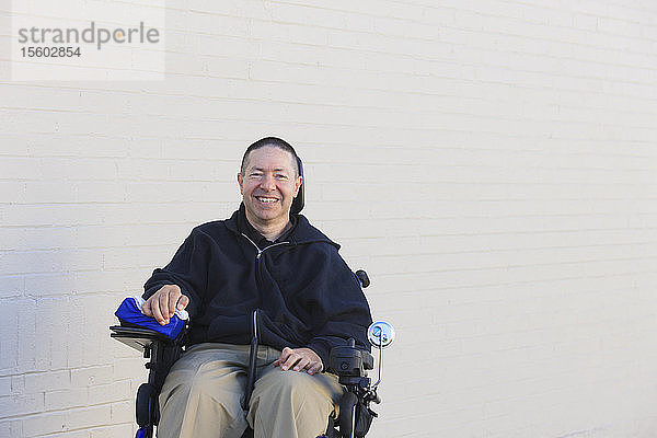 Mann mit Rückenmarksverletzung und Arm mit Nervenschaden im motorisierten Rollstuhl