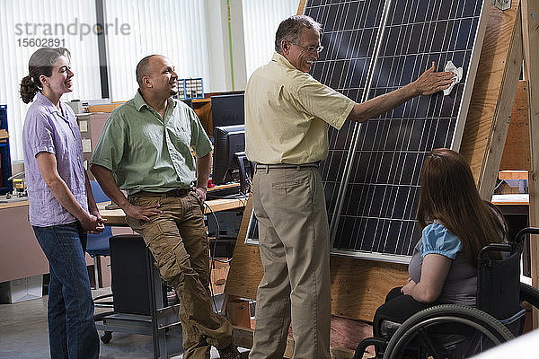 Ingenieurstudenten beobachten Professor bei der Reinigung eines Photovoltaikmoduls  um die Verbesserung des Wirkungsgrads zu demonstrieren