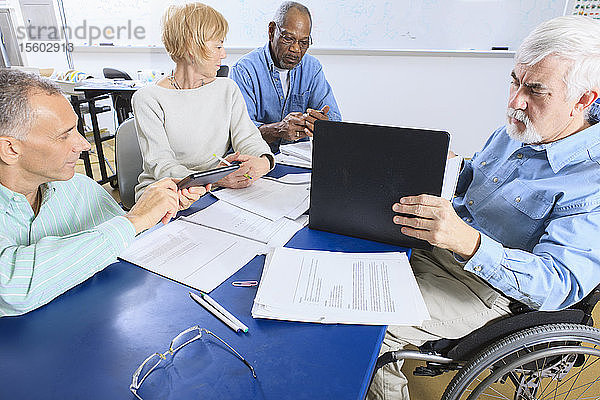 Professoren in einer Fakultätssitzung  einer im Rollstuhl mit Muskeldystrophie