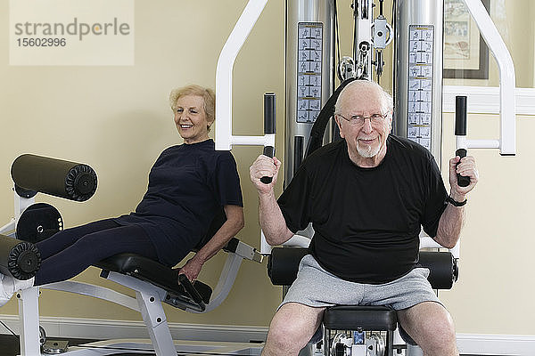 Ein älteres Paar trainiert im Fitnessstudio.