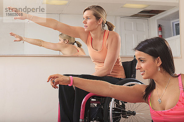 Junge Frauen mit Rückenmarksverletzungen dehnen sich in einem Yogastudio