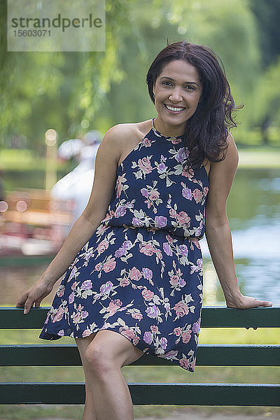 Porträt einer glücklichen hispanischen Frau  die in einem Park lächelt