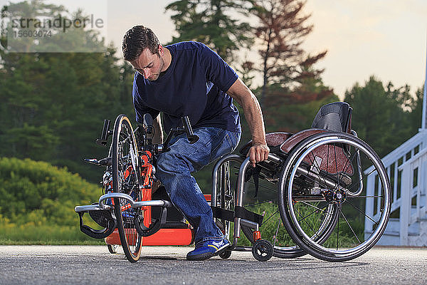 Ein Mann mit einer Rückenmarksverletzung in seinem Rollstuhl steigt auf sein speziell angefertigtes adaptives Handbike