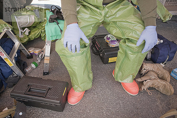 Tiefschnittansicht eines auf einem Hocker sitzenden HazMat-Feuerwehrmanns