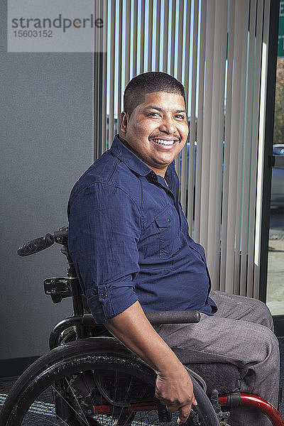 Hispanischer Mann mit Rückenmarksverletzung im Rollstuhl in einem Büro