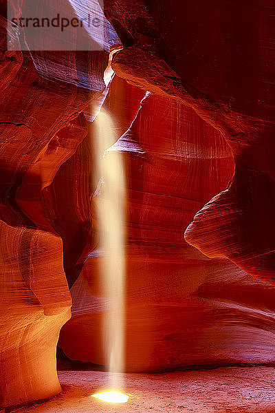 Upper Antelope Canyon mit einem Sonnenstrahl  der durch ein Loch  das einem Scheinwerfer ähnelt  auf den Boden scheint; Arizona  Vereinigte Staaten von Amerika