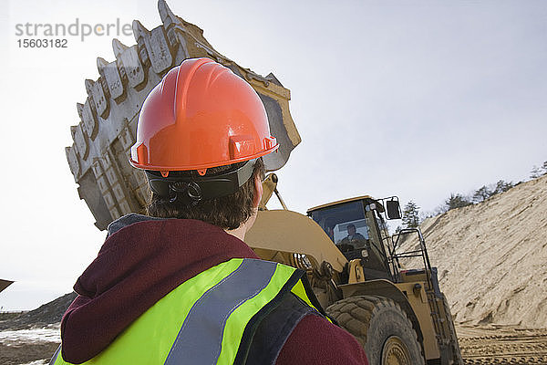 Ingenieur betrachtet einen Frontlader auf einer Baustelle